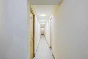 Un pasillo estrecho y bien iluminado, con puertas a ambos lados, que conduce a habitaciones.