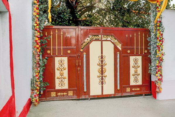Una reja roja y color crema con detalles dorados ornamentales y decoraciones florales.