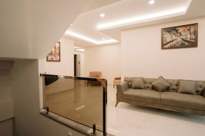 A modern living room with a sofa, a painting, and a glass partition. - Hotel Maneybung (Gangtok)