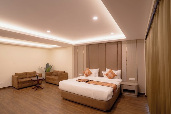 A modern hotel room with a large bed, a sofa, a small table, and a plant. - Hotel Maneybung (Gangtok)