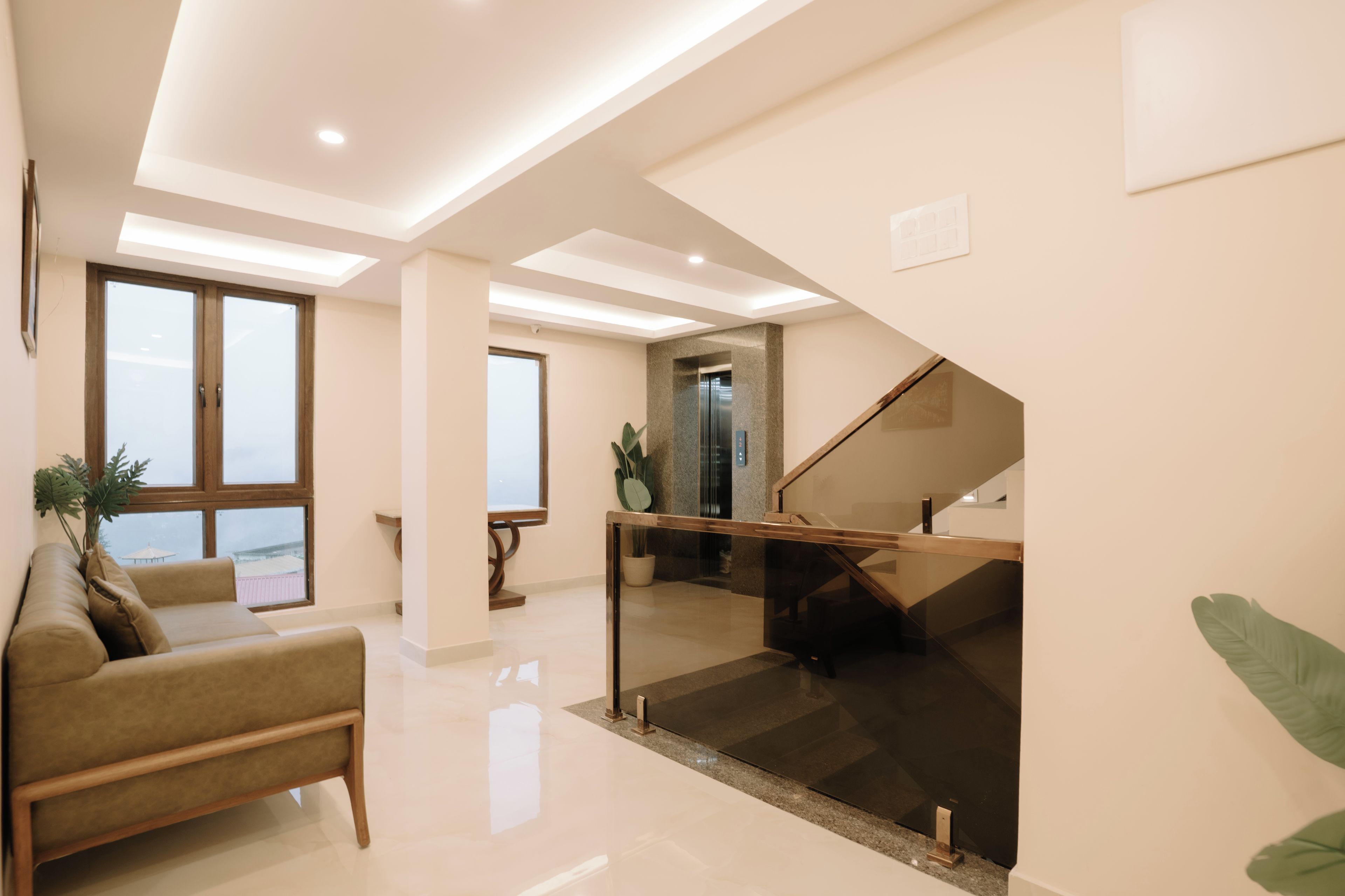 A modern interior with a staircase, a sofa, and a view through a glass door.
