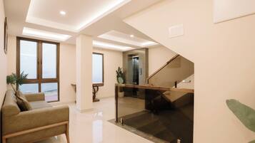 A modern interior with a staircase, a sofa, and a view through a glass door.