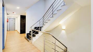 A modern interior with a staircase, wooden flooring, and a door with a fire extinguisher.