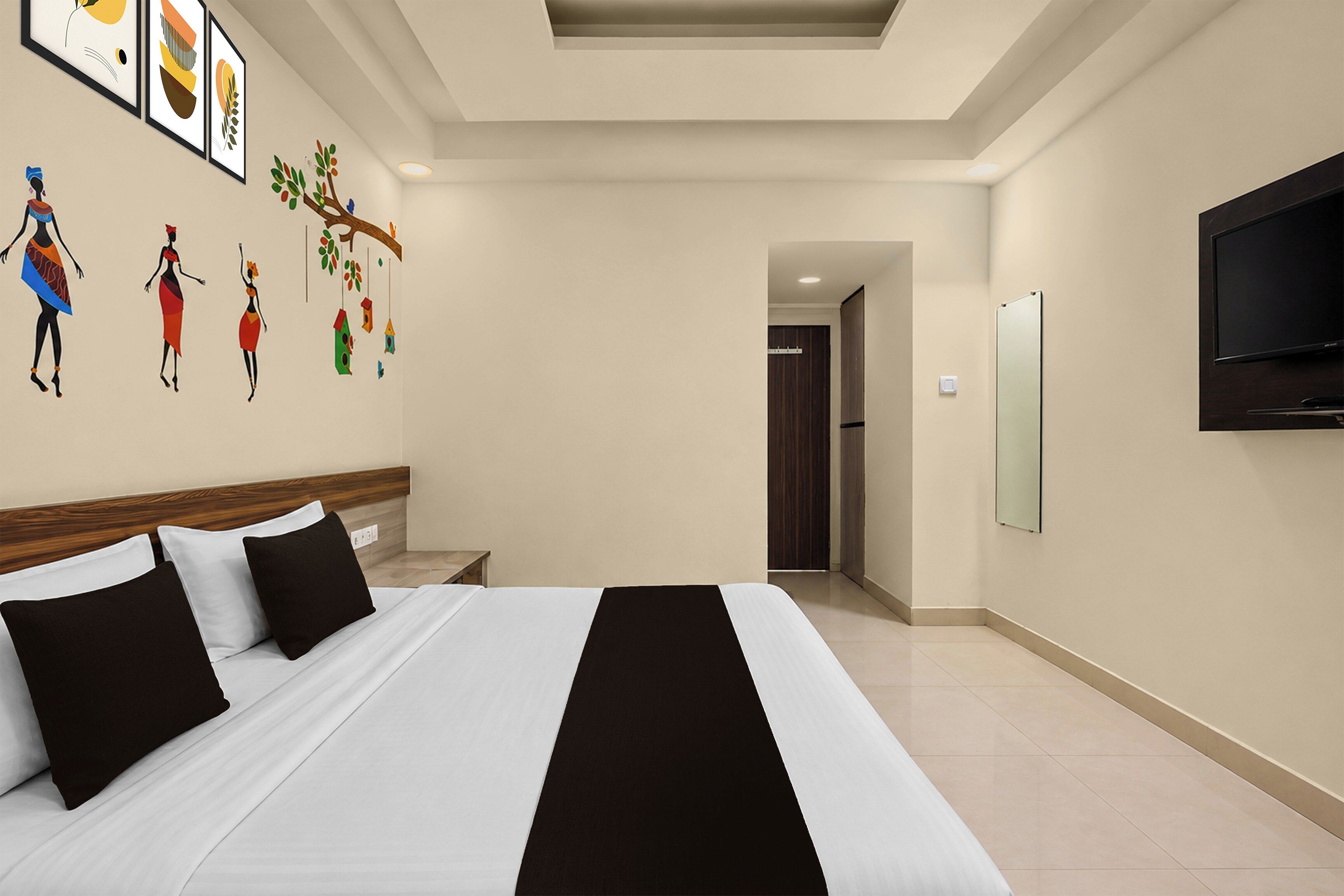 A hotel room with a bed, a TV, and a wall with artwork.