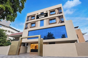 Uma casa geminada moderna com fachada de vidro ampla, entrada destacada com design geométrico e placa indicando que é administrada pela OYO.