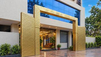 A modern building with a glass facade, a textured gold entrance, and a tiled ground.