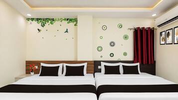 A hotel room with two beds, a wooden headboard, a wall with circular patterns, and a red curtain.