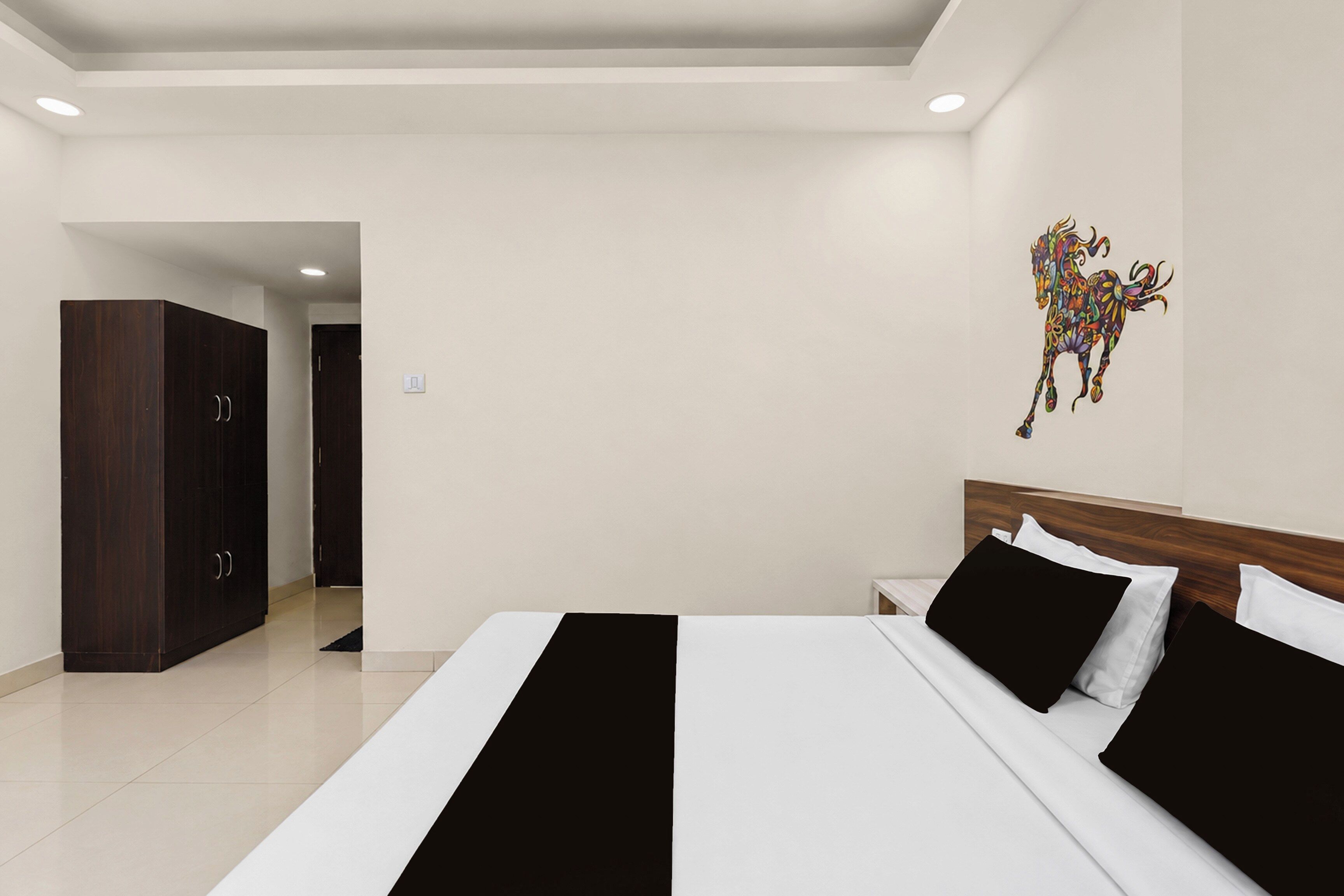 Habitación de hotel con una cama, una mesita de noche, un armario y una obra de arte colgada en la pared.