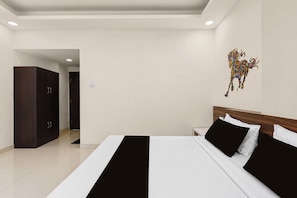 Quarto de hotel com cama, mesa de cabeceira, guarda-roupa e uma obra de arte na parede.