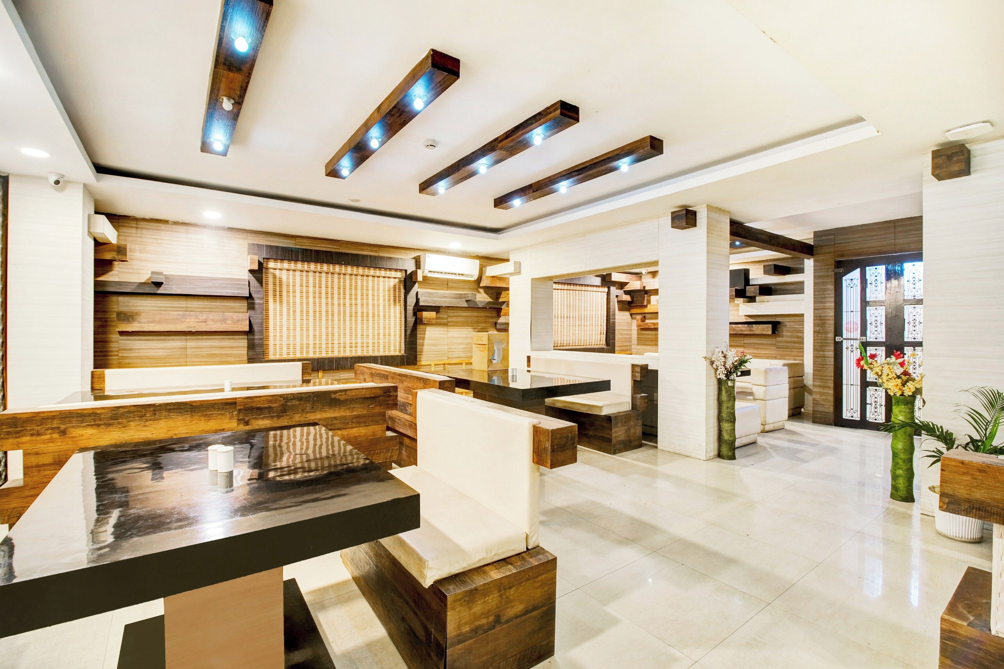 A modern hotel lobby with wooden accents, a reception desk, and a large window.