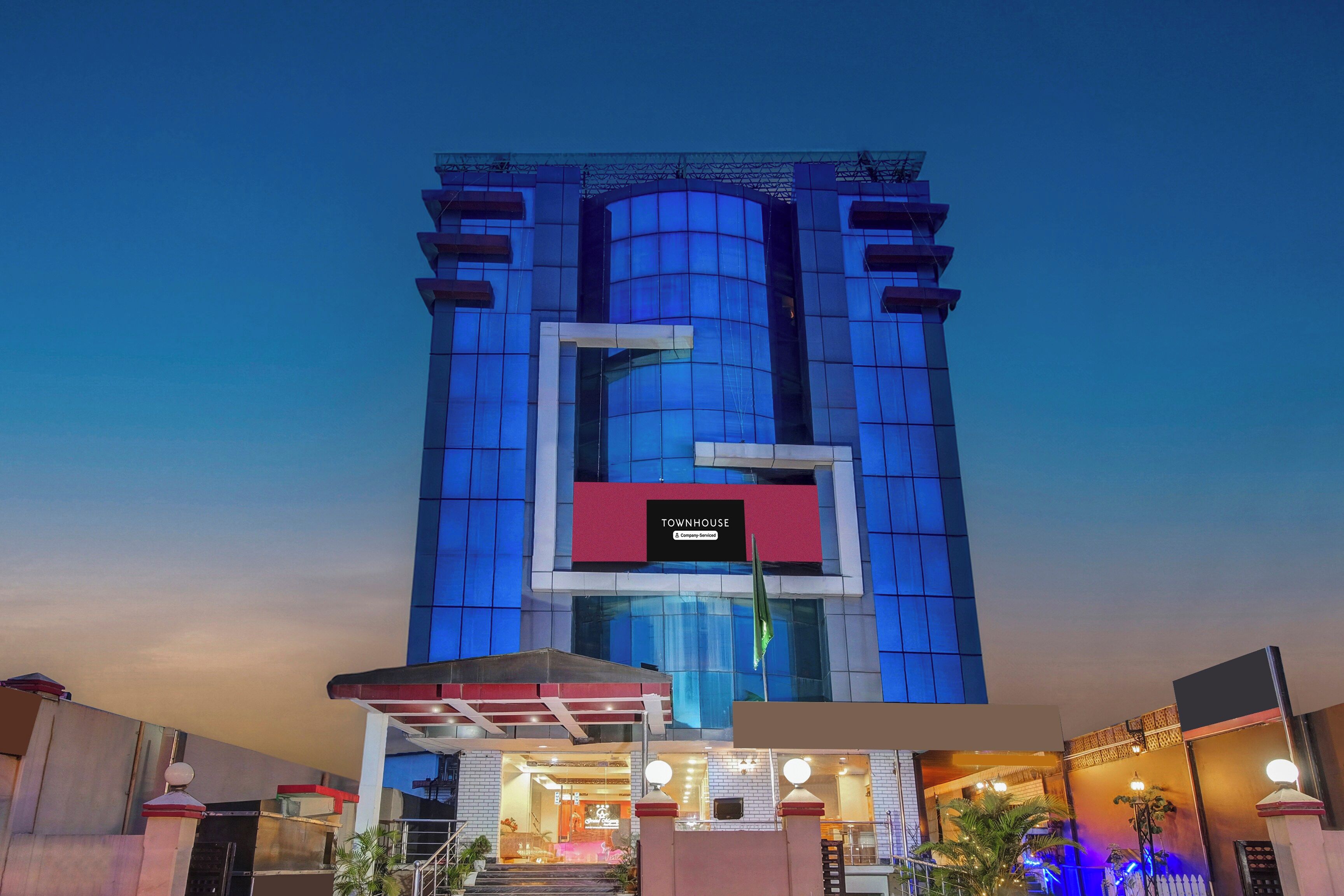 A multi-story hotel with a prominent 'TOURNHOUSE' sign, a glass facade, and a well-lit entrance.