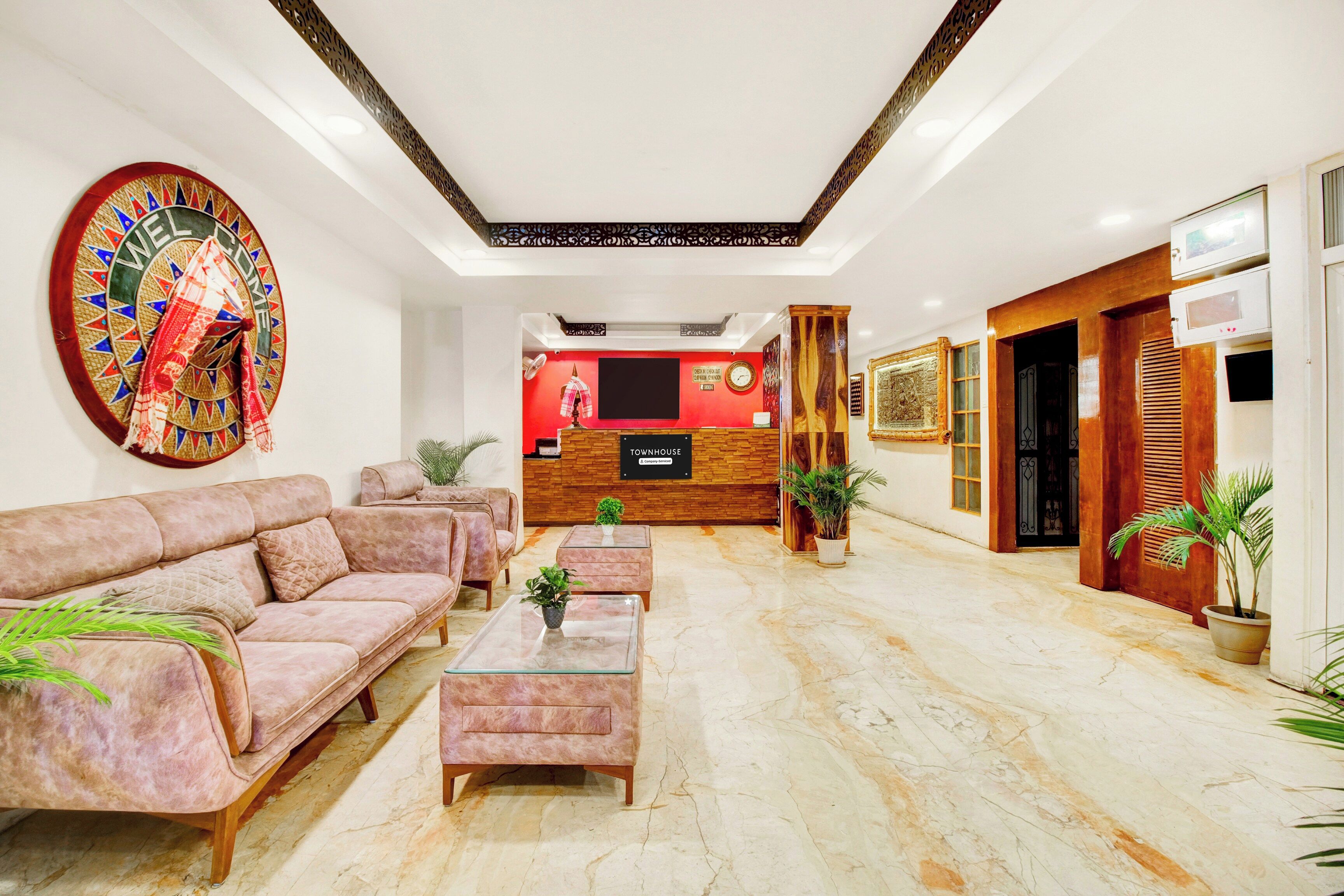 A hotel lobby with a reception desk, sofas, and a decorative wall.