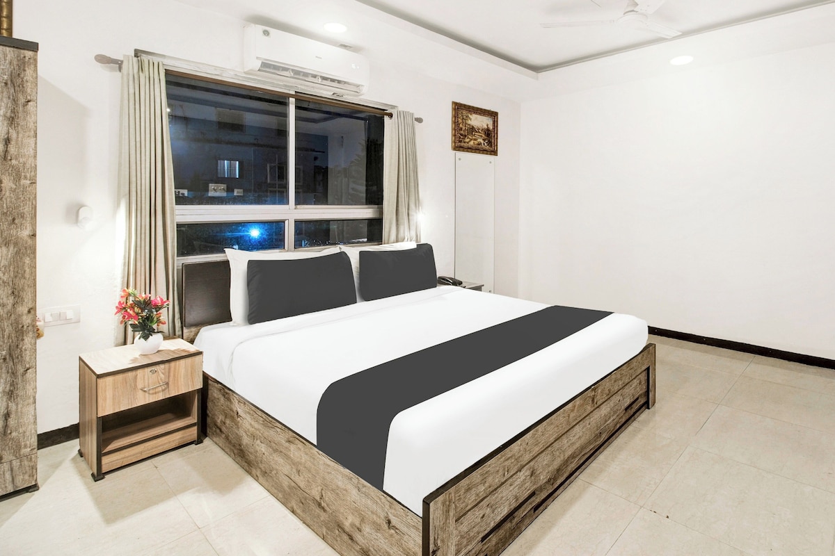 Un dormitorio moderno con una cama grande, una mesita de noche, una ventana con cortinas y un aire acondicionado de pared.