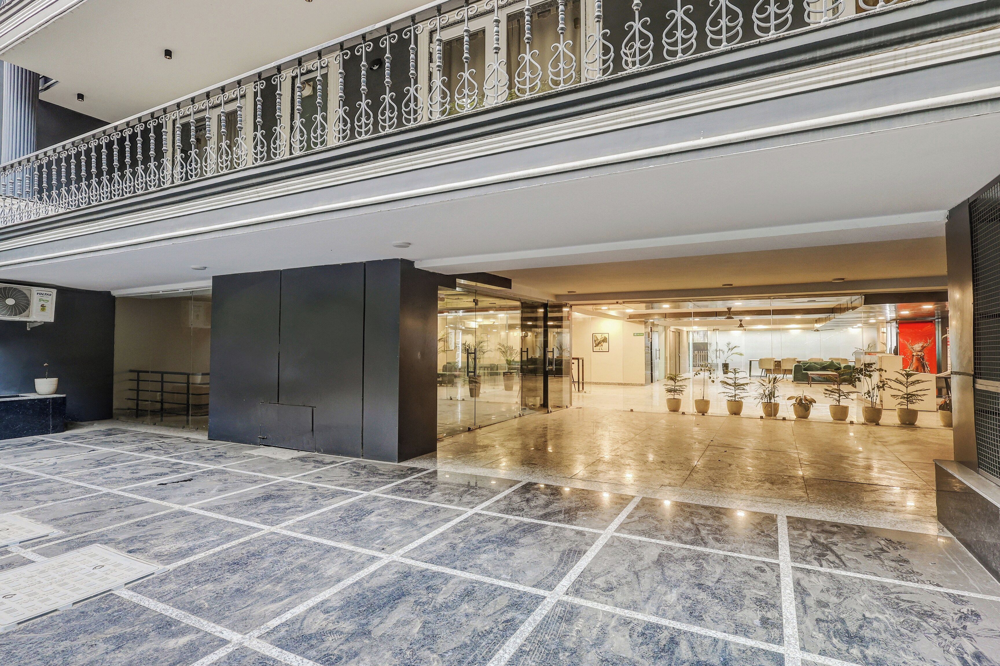 A spacious lobby with a marble floor, a glass entrance, and a decorative railing.