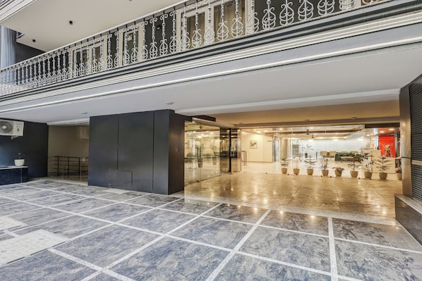 A spacious lobby with a marble floor, a glass entrance, and a decorative railing. - Townhouse Oak Udyog Vihar (Gurugram)