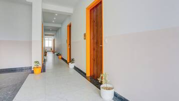 Un pasillo con puertas, plantas en macetas y piso de baldosas.