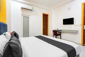 Una habitació d'hotel amb un llit, un escriptori amb una cadira, una televisió i un aparell d'aire condicionat.