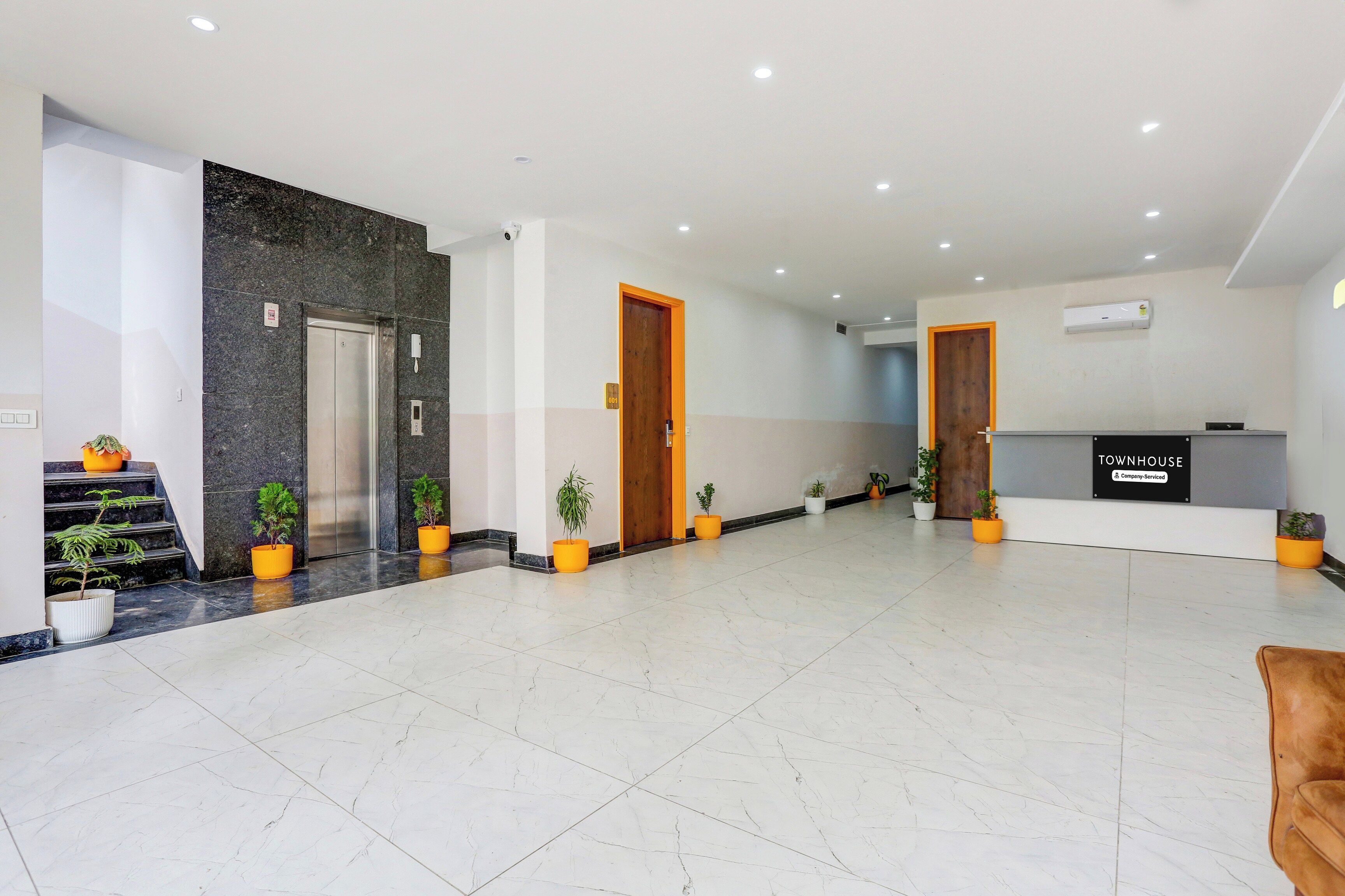 Rebedor d'hotel amb taulell de recepció, escala i zona d'espera.