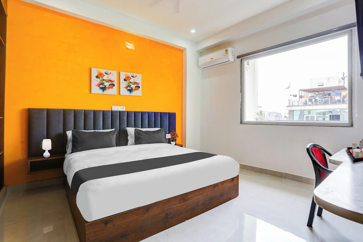 Habitació d'hotel amb un llit, una taula de nit, una làmpada, una finestra amb vista i dues obres d'art murals.