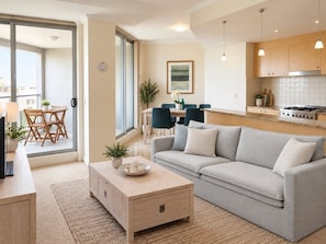 A modern living room with a sofa, coffee table, and a dining area with chairs and a table. - HELP2 - Chatswood Convenience | Steps To Train & Metro (Chatswood)