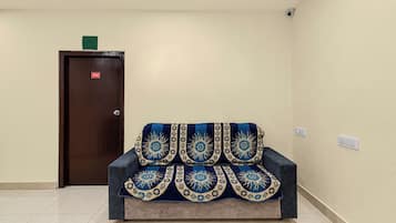 Una habitación con un sofá, una puerta con el símbolo del número y una lámpara en el techo.