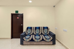 Una habitación con un sofá, una puerta con el símbolo del número y una lámpara en el techo.