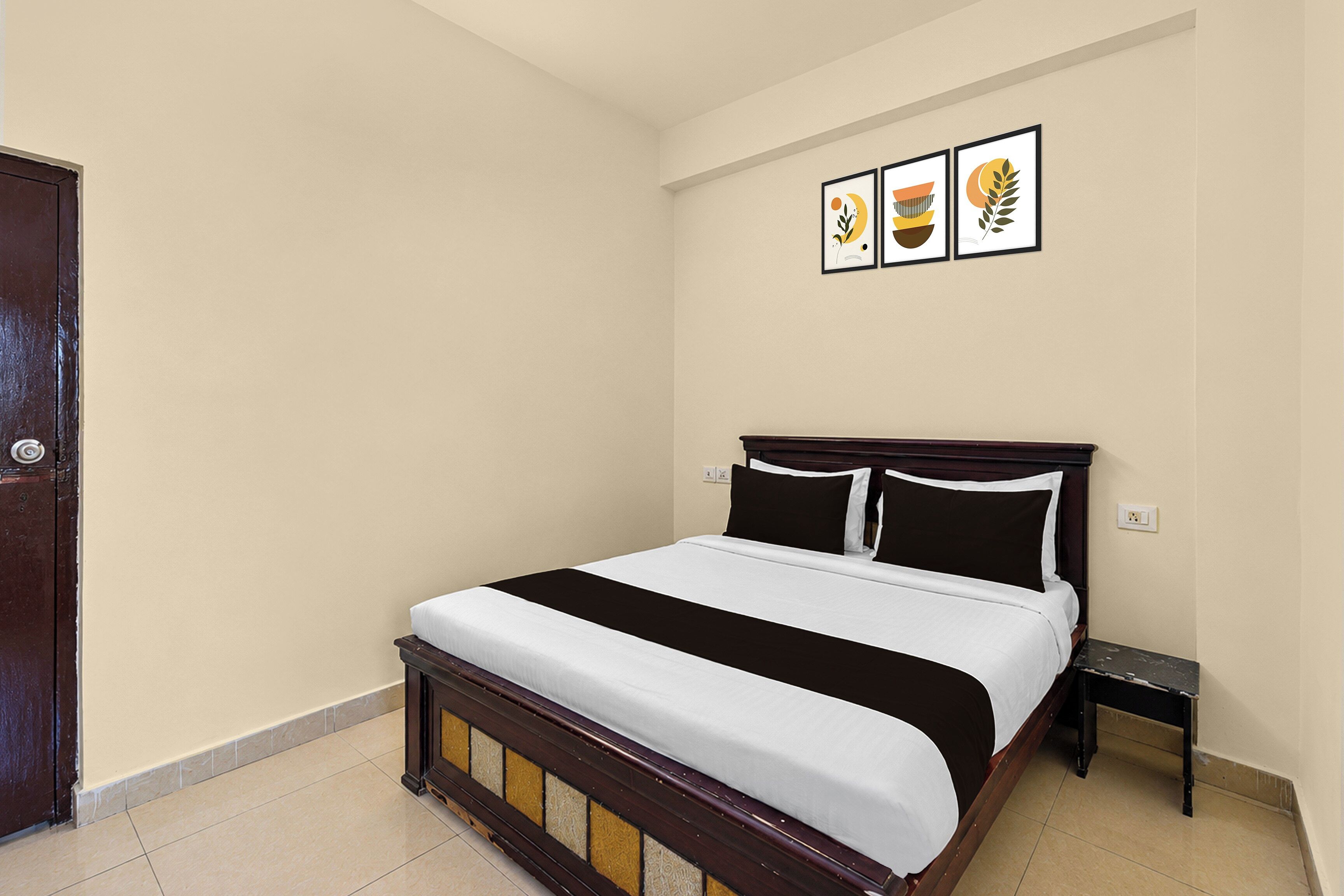 Un dormitorio con una cama, una mesita de noche y tres cuadros en la pared.