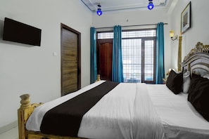 Ein Hotelzimmer mit Bett, Tür, einem Vorhangfenster und einer Wandleuchte.