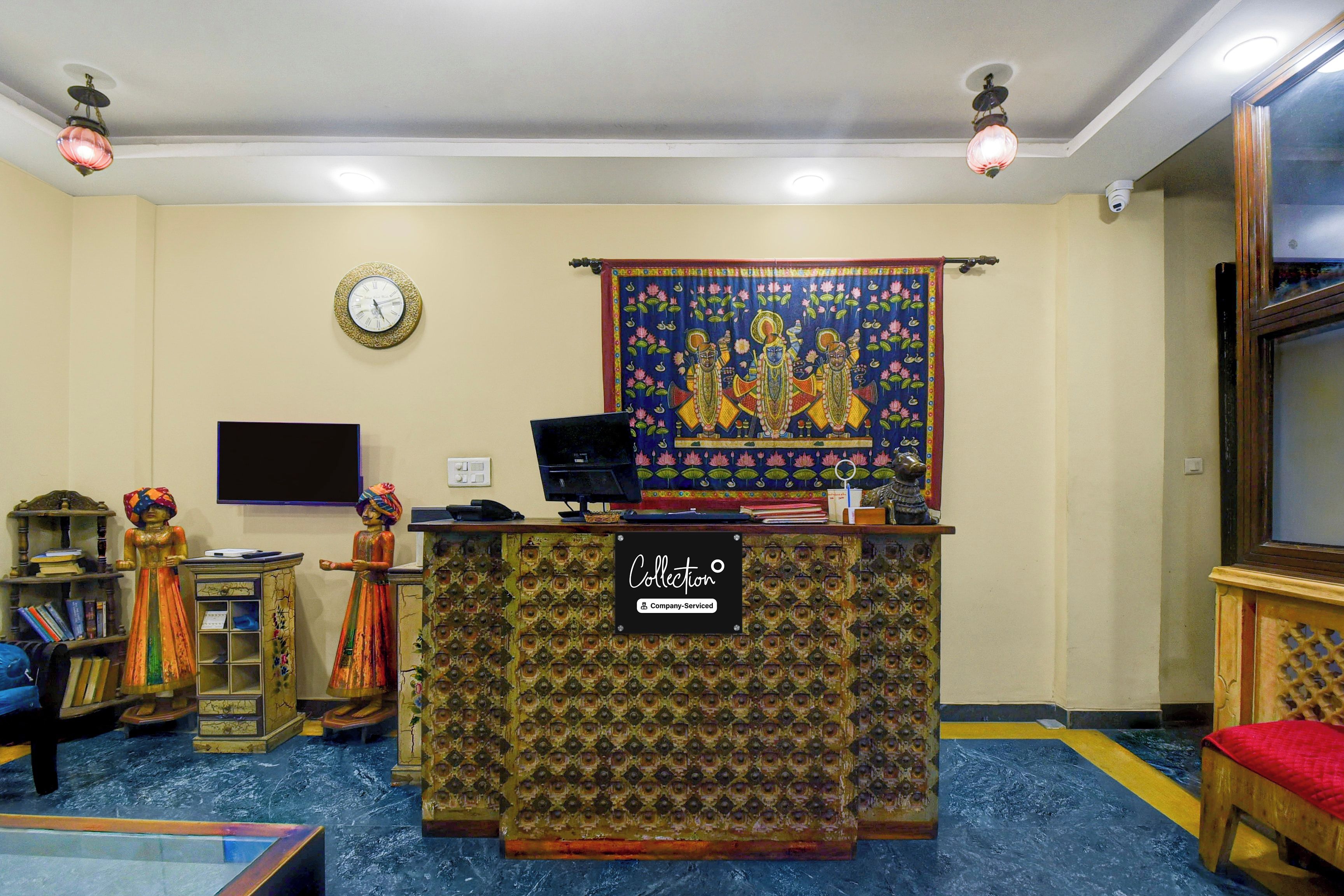 Un área de recepción con un escritorio estampado, un reloj, un tapiz y decoración tradicional.