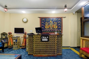 A reception area with a patterned desk, a clock, a tapestry, and traditional decor. - Collection O Jal Mahal Jaipur (Jaipur)