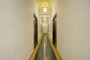 A hotel hallway with a central yellow line, doors on both sides, and a patterned ceiling light fixture. - Collection O Jal Mahal Jaipur (Jaipur)