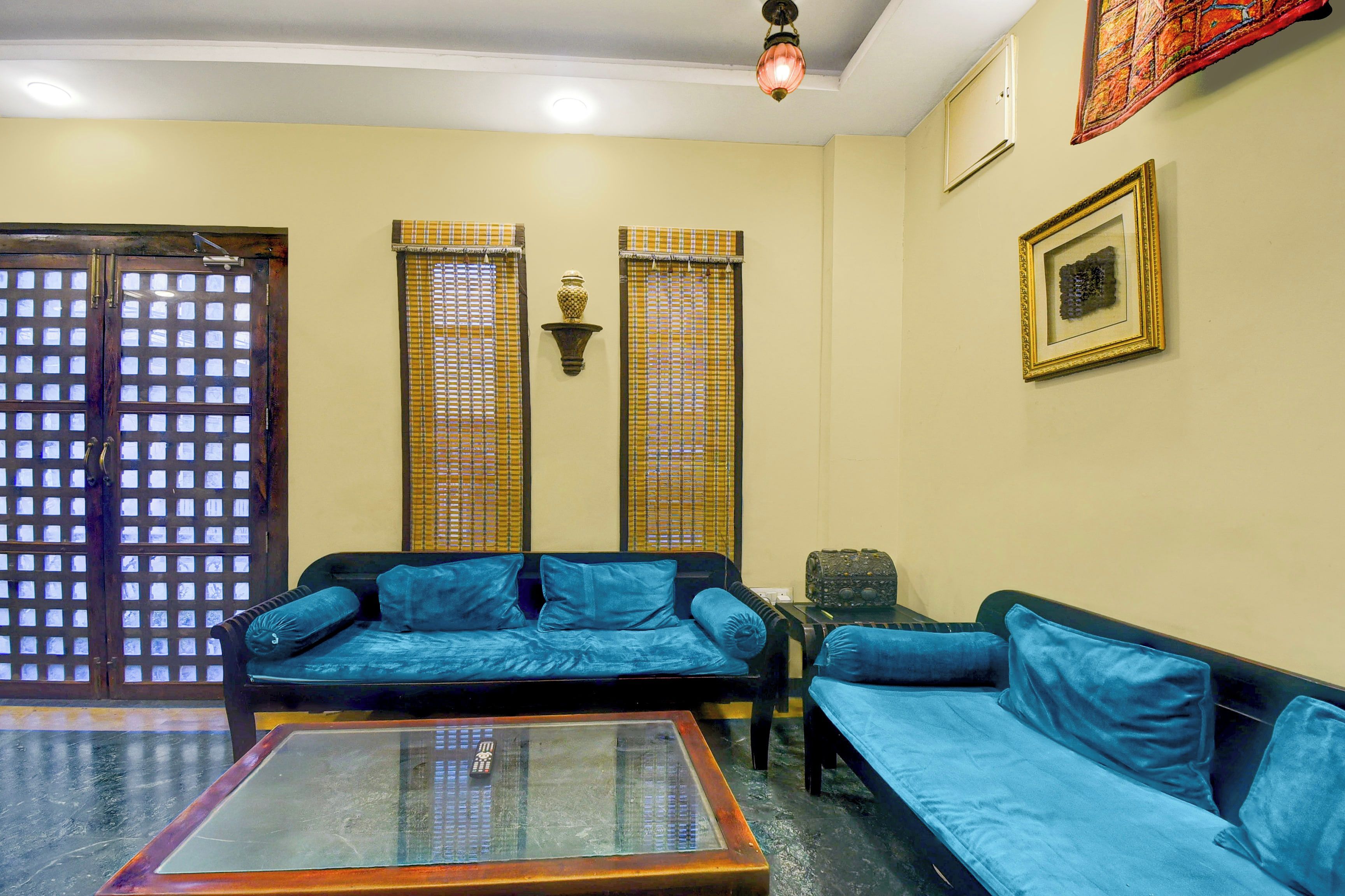 A living room with a sofa set, a coffee table, a wall-mounted lamp, and a door with a grid pattern.