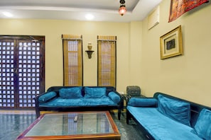A living room with a sofa set, a coffee table, a wall-mounted lamp, and a door with a grid pattern. - Collection O Jal Mahal Jaipur (Jaipur)