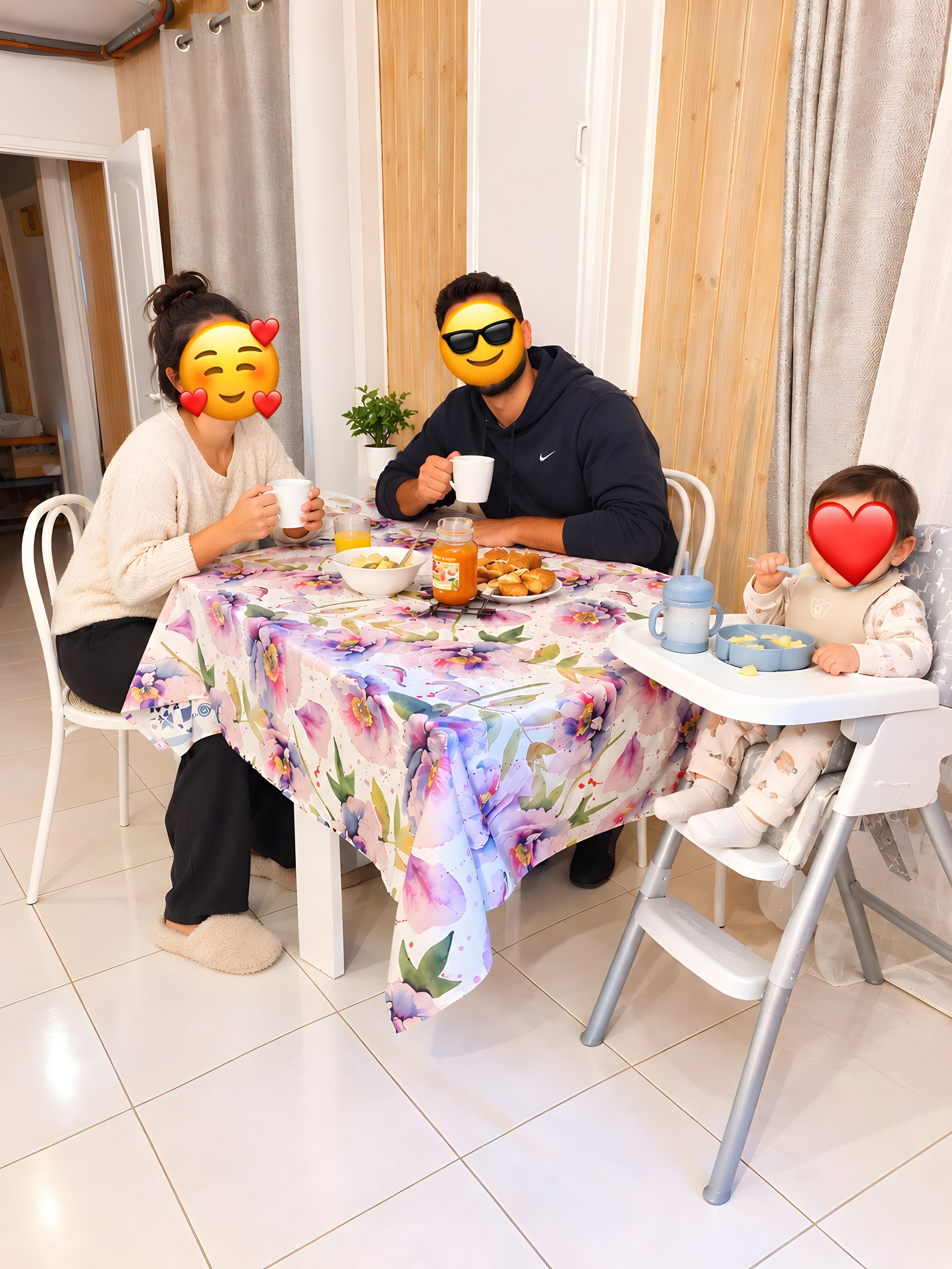 Un tavolo da pranzo con tovaglia floreale, una pianta in vaso e un bambino in seggiolone.