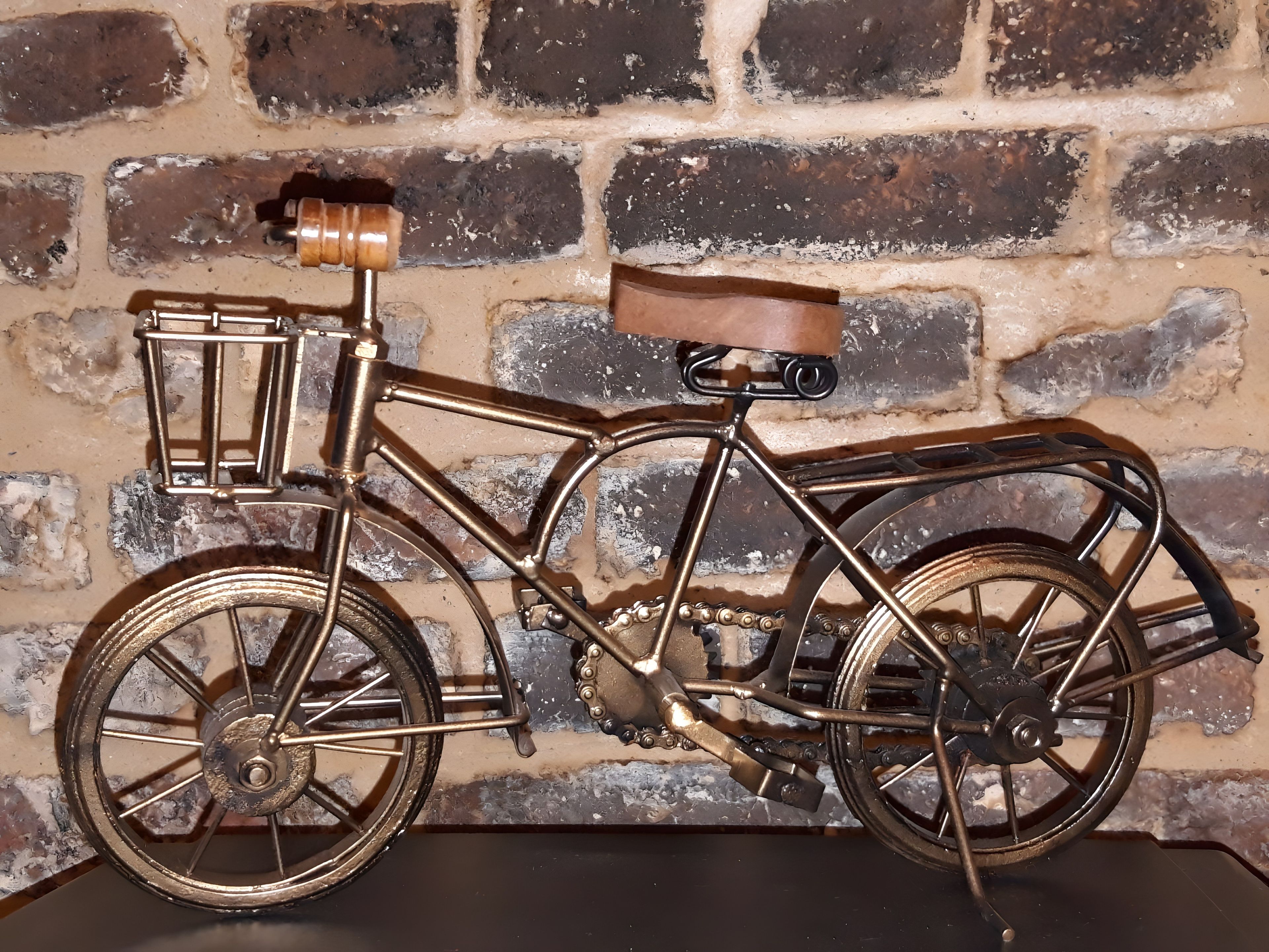 En cykel i vintage-stil med en korg och ett sadel, monterad på en tegelvägg.