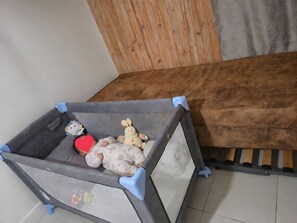 A baby playpen with a mesh bottom, a plush toy, and a red heart-shaped pillow.
