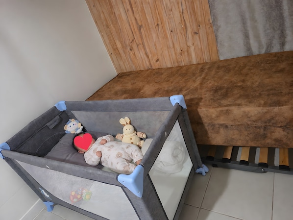 A baby playpen with a mesh bottom, a plush toy, and a red heart-shaped pillow.