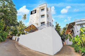 A modern hotel with a prominent 'HOTEL' sign, a white facade, and a sloped roof.