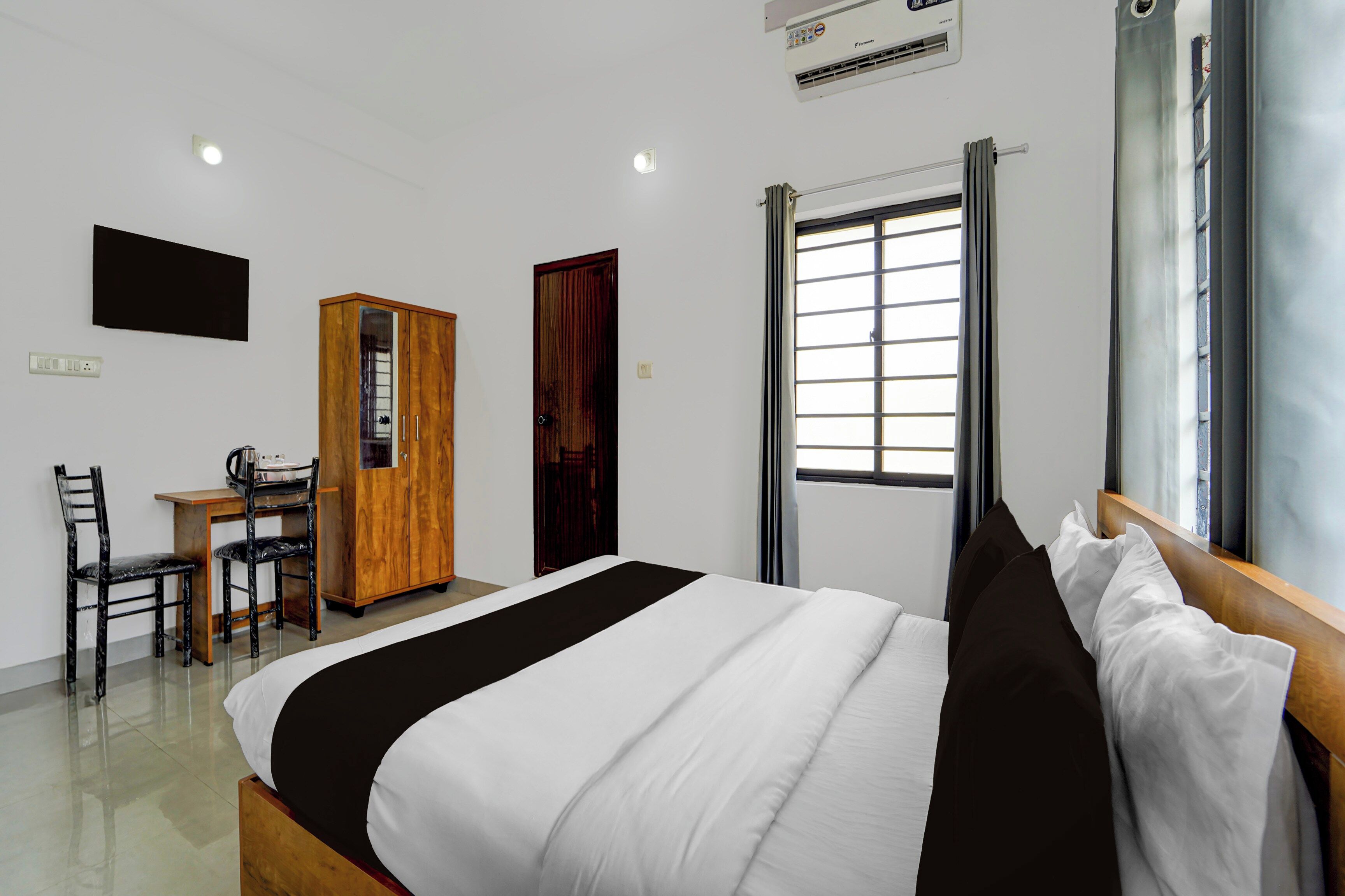 Une chambre d’hôtel avec un lit, un bureau, une armoire et une fenêtre avec des rideaux.