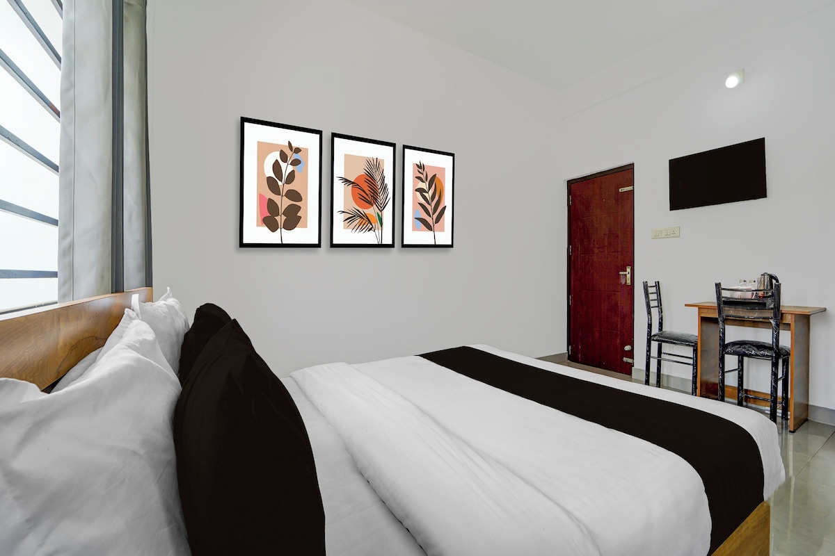 Una habitación de hotel con cama, escritorio y televisión en la pared.