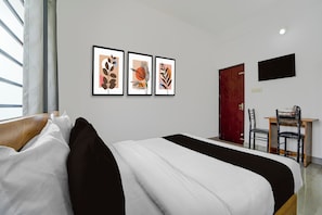 Una habitación de hotel con cama, escritorio y televisión en la pared.