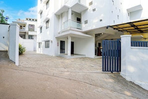 A multi-story residential building with a gated entrance, a covered porch, and a visible staircase leading to the upper floors. - Super Hotel O Kinfra Industrial Park (Calicut)