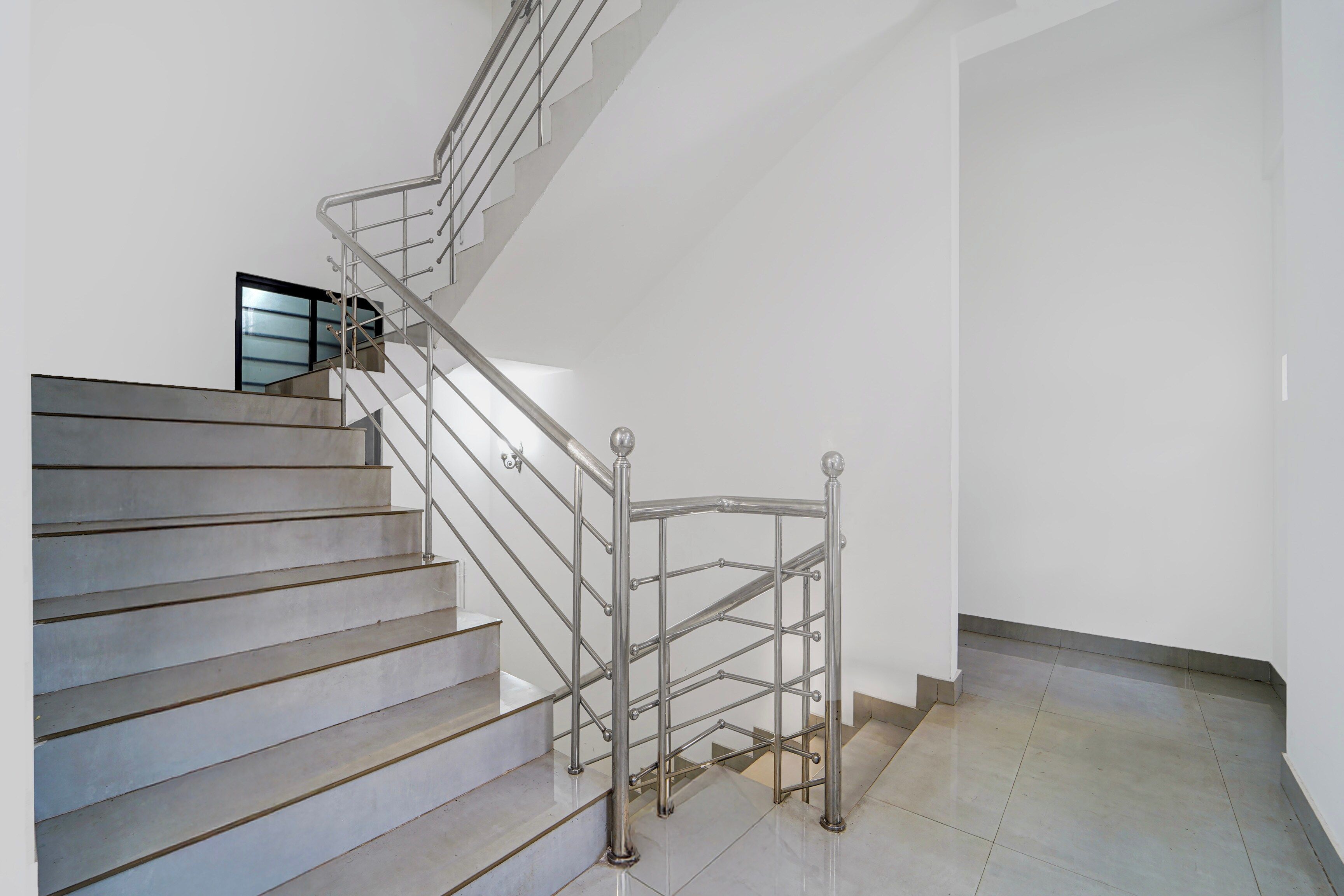 A staircase with metal railings and a handrail, leading to a landing with a door.
