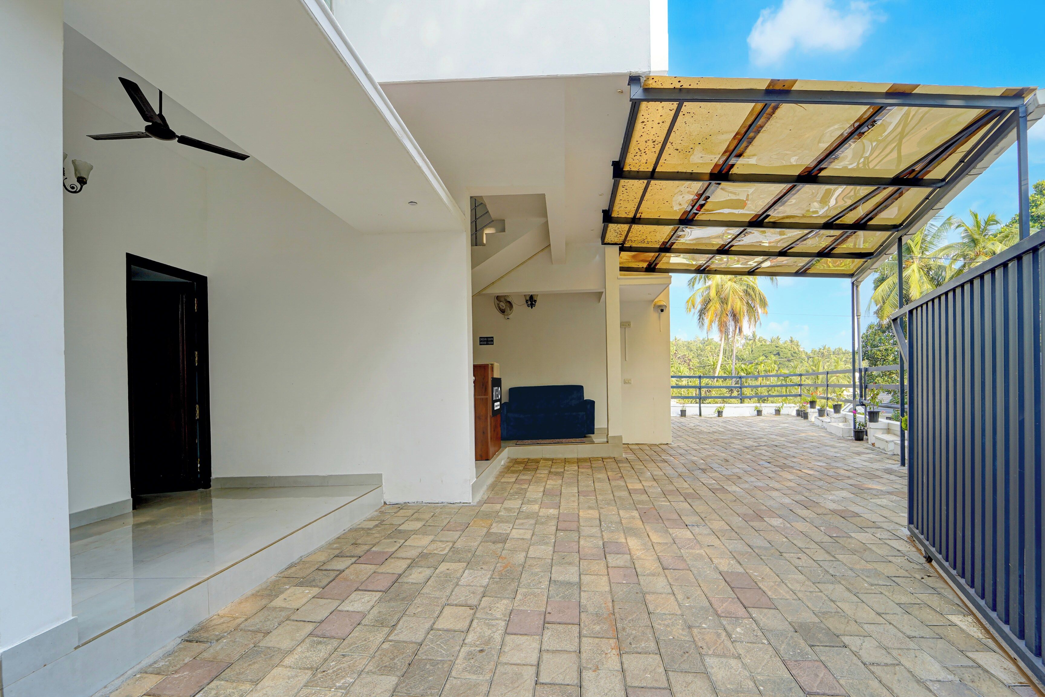 A covered outdoor area with a tiled floor, a black door, and a blue sofa.