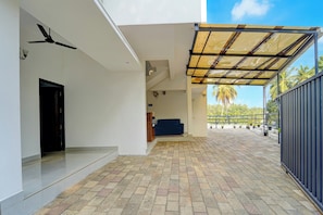 A covered outdoor area with a tiled floor, a black door, and a blue sofa. - Super Hotel O Kinfra Industrial Park (Calicut)