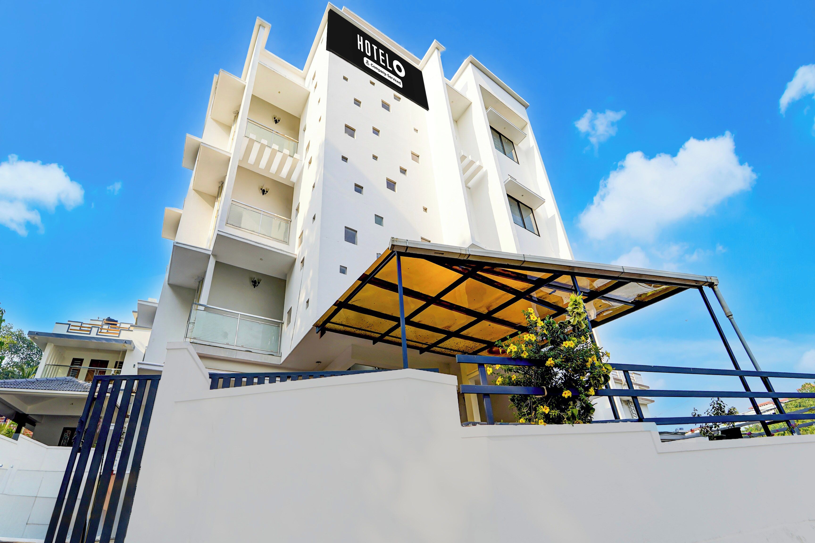 Un moderno edificio de hotel con un letrero llamativo, varios balcones y una zona de entrada cubierta.