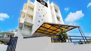 Un moderno edificio de hotel con un letrero llamativo, varios balcones y una zona de entrada cubierta.