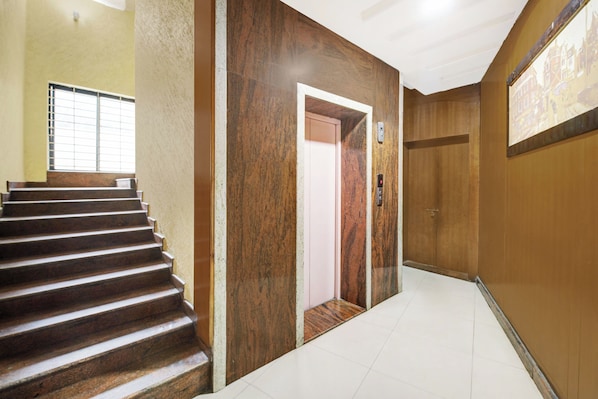 A staircase leading to an elevator in a building with a tiled floor and wooden walls.