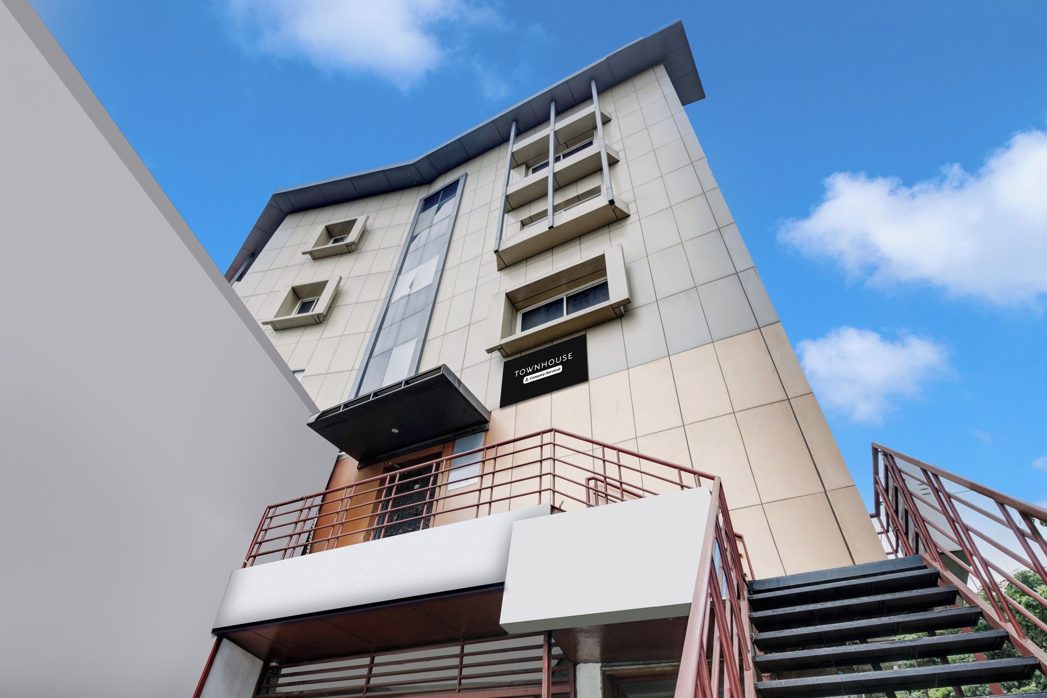 A multi-story building with a modern design, featuring a prominent staircase and a sign indicating a company-serviced property.
