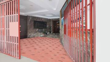 Corredor de hotel com esquema de cores vermelho e branco, parede de mármore e piso estampado.